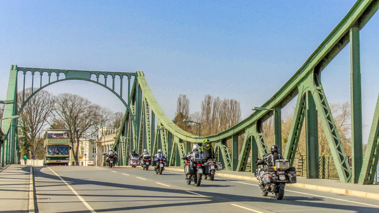 Motorradgruppe fährt über eine grüne Stahlbrücke