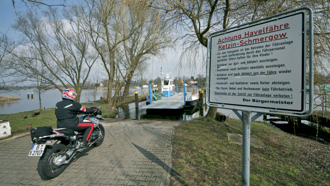 Motorrad an einer Anlegestelle, daneben ein Schild der Havelfähre Ketzin–Schmergow